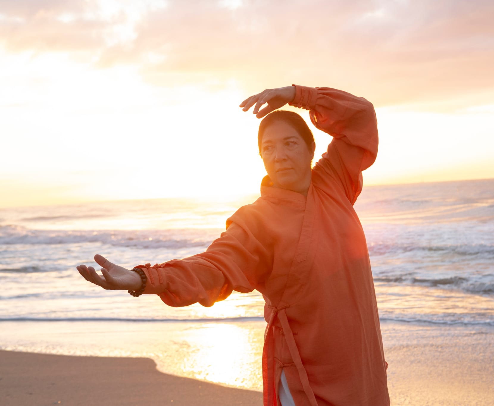 mujer practicando qigong ante la puesta de sol